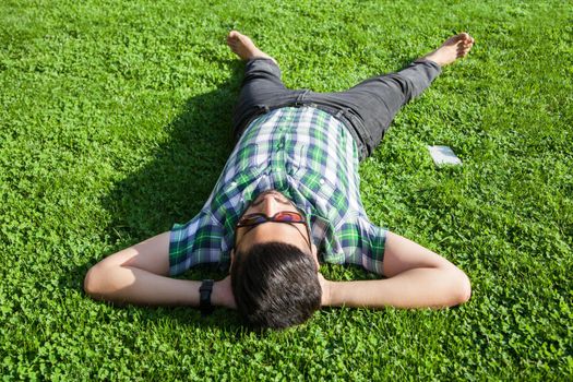 young man lie down on lawn and enjoying summertime.