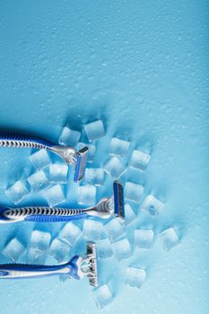 Blue shaving machines in a row on a blue background with ice cubes. The concept of cleanliness and frosty freshness