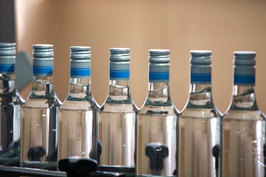 A long row of glass bottles on a conveyor belt. Production of alcoholic beverages.
