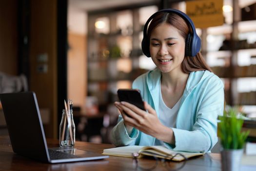 photo of woman wearing headphones and using mobile phone for online learning - educational course or training, seminar, education online concept.