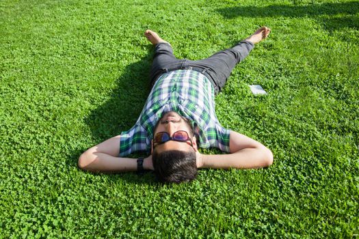 young man lie down on lawn and enjoying summertime.