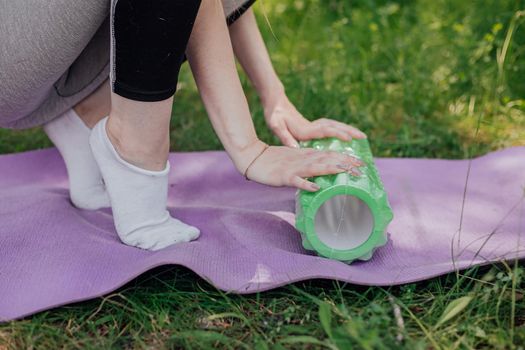 Woman practicing yoga and meditating outdoors. Girl preparing material for practice class in garden. Female happiness and yoga concept. During the quarantine due to the spread of the coronavirus