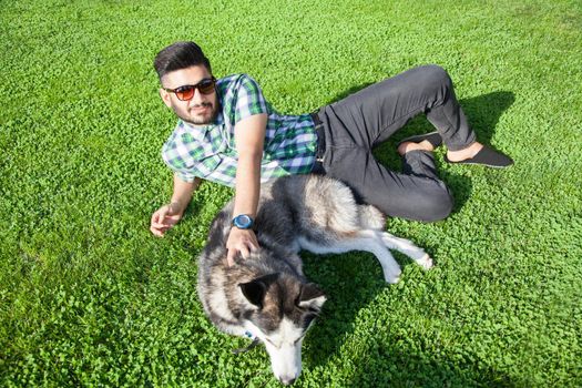 Young man sitting at green lawn and enjoying with his dog