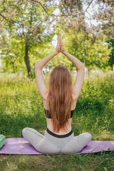 Yoga woman on green grass girl relaxes in the field. Yoga woman in green park girl doing gymnastics outdoors. Meditating woman in meditation in yoga pose practices outdoors