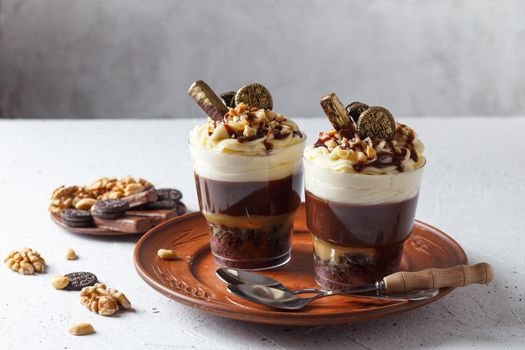 Delicious chocolate trifle or pudding with whipped cream in a glass on a gray background.