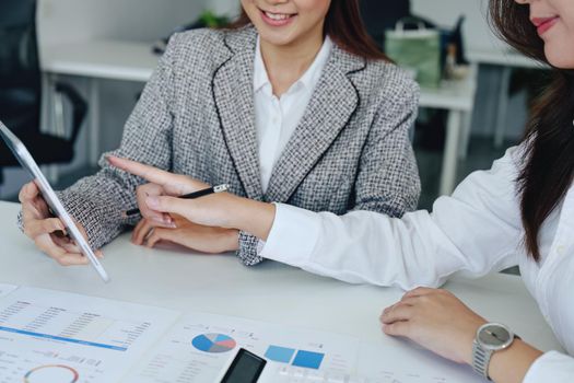 young Asian businesswoman using tablet computers to plan marketing strategies and invest to profit from customers.