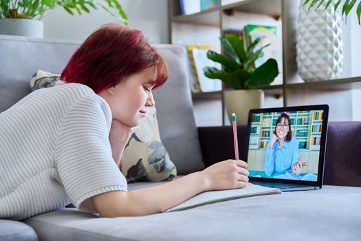 Teenage female student at home looking listening online lesson webinar teacher on laptop screen. Virtual communication, video call chat conference. E-education technology adolescence distance learning