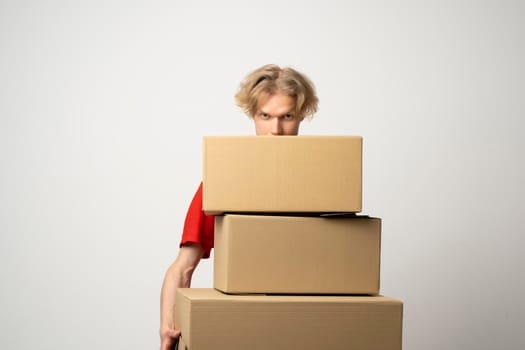 Young delivery man standing with lot of parcel post boxes isolated over white background