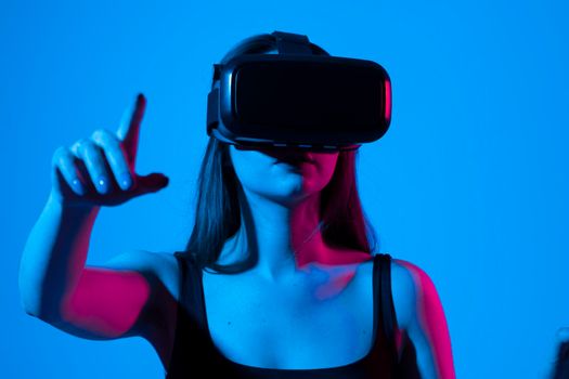 Amazed happy brunette girl in black t-shirt getting experience using VR headset glasses of virtual reality and exploring a new cyber worlds