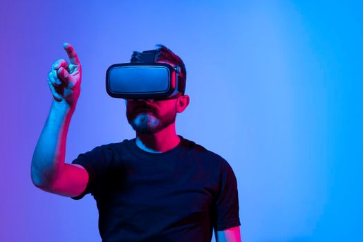 Amazed young bearded man, wearing high tech smart vr goggles, watching 360 degree video or playing a video game in metaverse