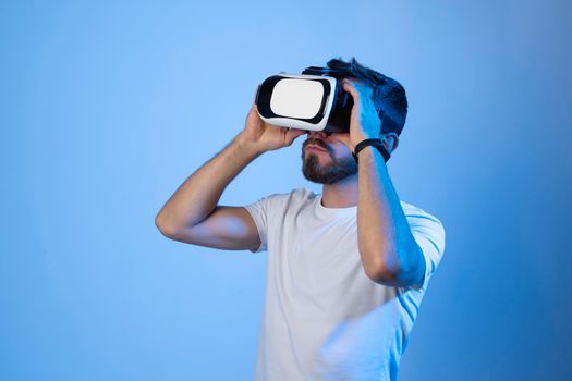 Amazed young bearded man, wearing high tech smart vr goggles, watching 360 degree video or playing a video game in metaverse