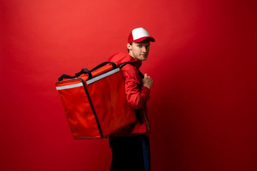 Delivery courier with red food backpack deliver food orders. Man delivering fast food with thermal backpack. Food delivery courier