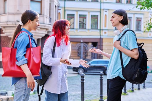 Meeting teenage friends outdoor, on street of city. Happy laughing talking young females and guy. Youth, communication, friendship, emotions, high school, college concept