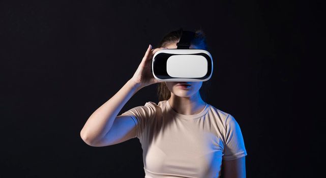 Young beautiful woman wearing a VR headset and experiencing a virtual reality simulation, metaverse and cyberspace concept