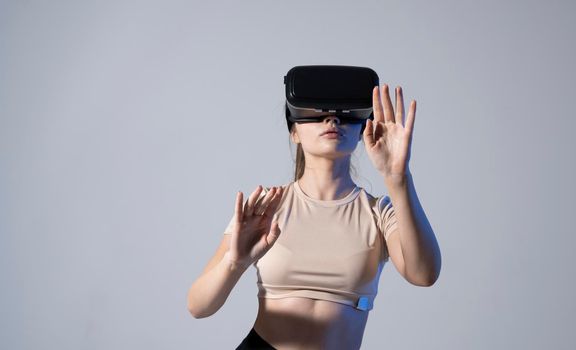 Young beautiful brunette woman wearing a VR headset and experiencing a virtual reality simulation, metaverse and cyberspace concept. Future technology concept