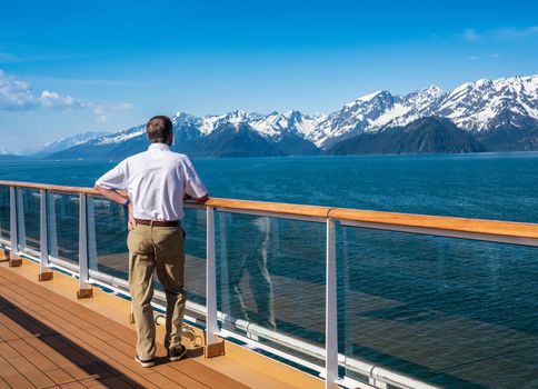 Senior adult man alone on deck of cruise ship leaving Alaskan port of Seward