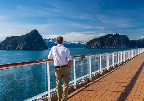 Senior adult man alone on deck of cruise ship leaving Alaskan port of Seward