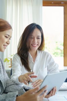 Portrait of a young Asian businesswoman using tablet computers to plan marketing strategies and invest to profit from customers.