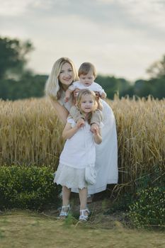 Mother playing with children in a wheat field Countryside