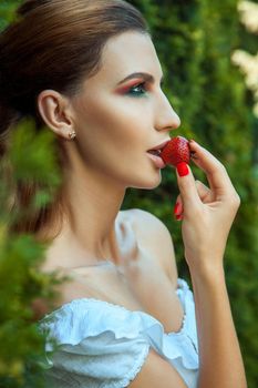 Fashionable passion woman eating red sweet strawberry. Outdoor spring or summer photo