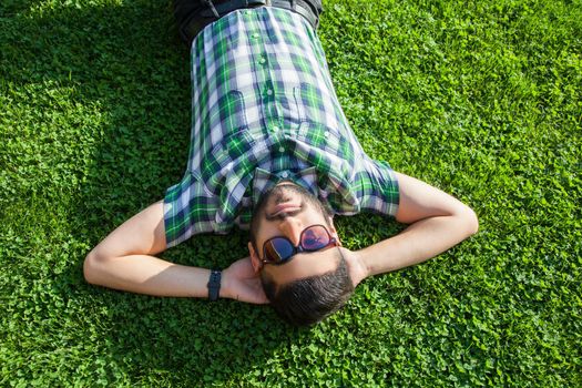 young man lie down on lawn and enjoying summertime.