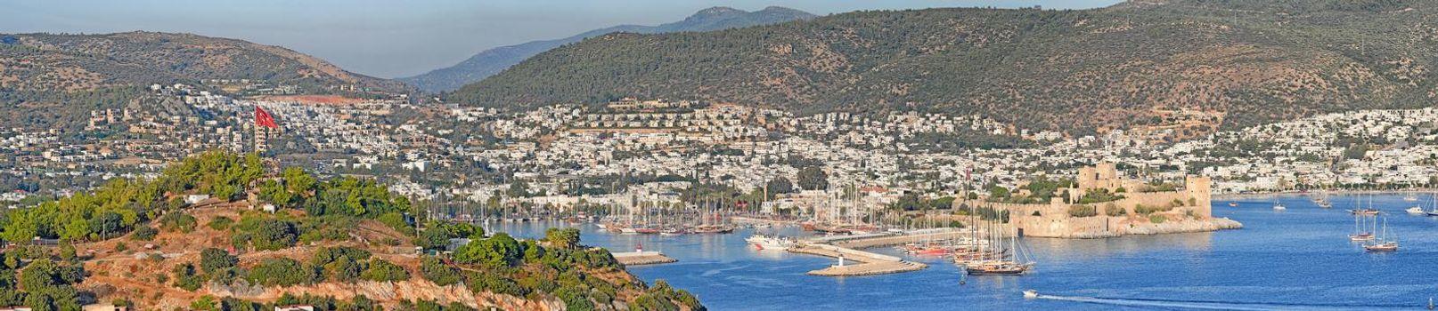 Panorama view of city and hills in romantic harbor of Bodrum in Turkey during the day. Scenic landscape view of sailing yachts in cruise port and bay. Tourism abroad, overseas in Aegean sea dockyard.