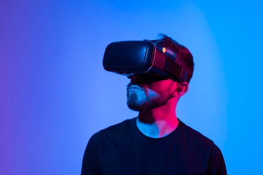 Amazed young bearded man, wearing high tech smart vr goggles, watching 360 degree video or playing a video game in metaverse