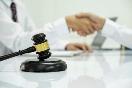 Businessman Shaking hands with Professional male lawyer after discussing good deal of contract in courtroom, Concepts of law, Judge gavel with scales of justic, Legal services advice at the law office.