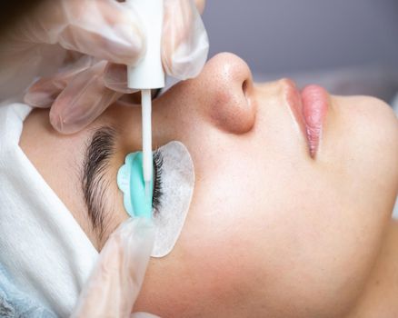 Young woman undergoing eyelash tinting and lamination procedure