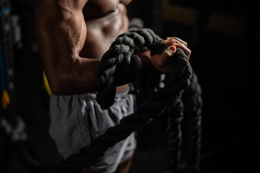 Muscular african american man posing with rope in gym