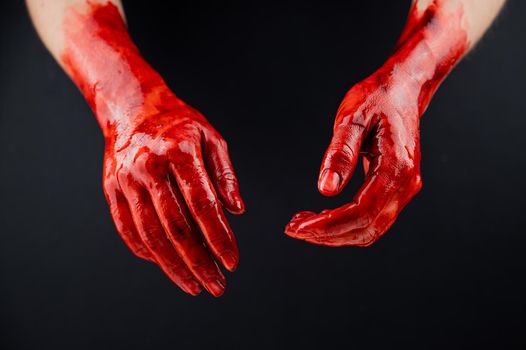 Women's hands in blood on a black background