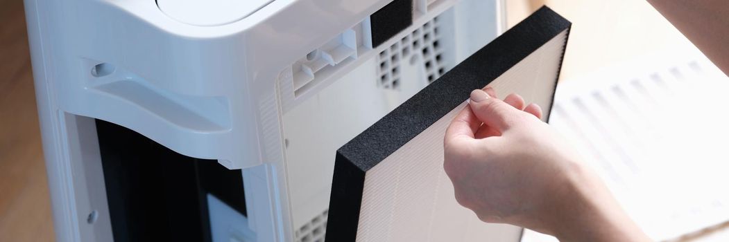 A woman removes the filter from the air ionizer, close-up. Household appliances, air purification, air conditioning, equipment
