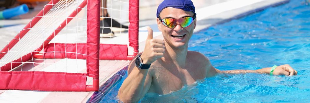 Sports man in the pool smiling and showing thumbs up, close-up. Polo player, goalkeeper. Team play, swimming