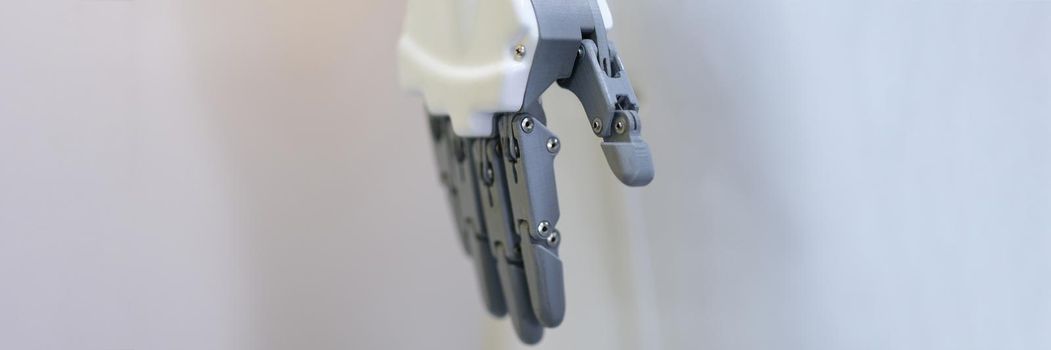 Robotic hand with fingers on a white background, close-up. Industrial manipulator, sensor, flexible simulator