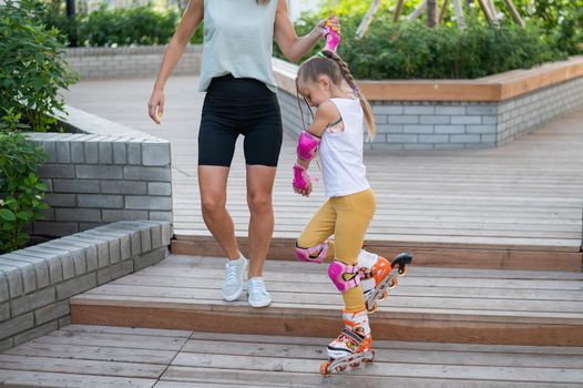 Caucasian woman teaches her daughter to skate on roller skates