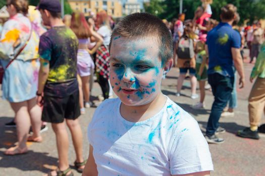 Novokuznetsk, Kemerovo region, Russia - June 12, 2022 :: Boy with colorful face painted with holi powder having fun outdoors.