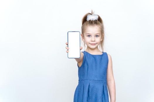 Little kid girl 6 years old in casual clothes hold mobile cell phone with blank screen workspace on grey background . Childhood lifestyle concept.