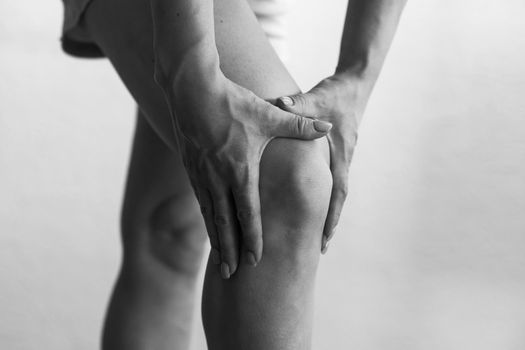 Closeup woman hand hold knee with pain symptom, health care and medical concept.