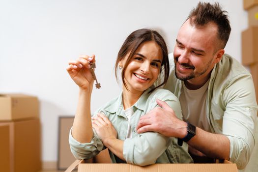 Young happy couple in room with lots of moving boxes at new home