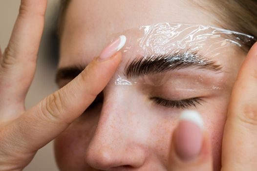 The master uses a plastic film during lamination of the eyebrows