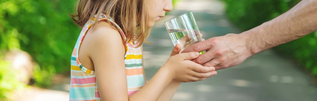 The father gives the child a glass of fresh water. Selective focus. nature.