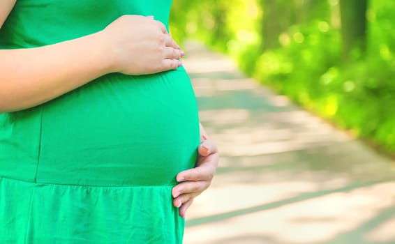 Pregnant woman in the park on the background of the road. Selective focus. people.