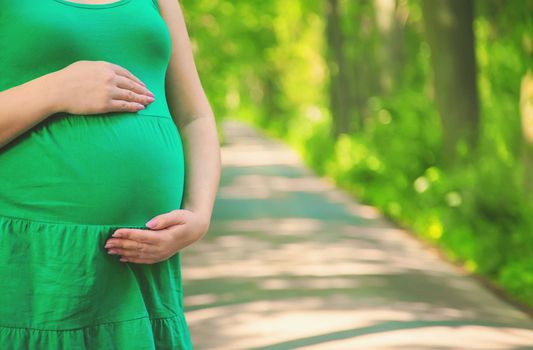 Pregnant woman in the park on the background of the road. Selective focus. people.