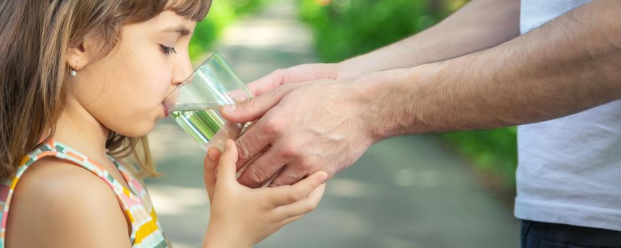 The father gives the child a glass of fresh water. Selective focus. nature.