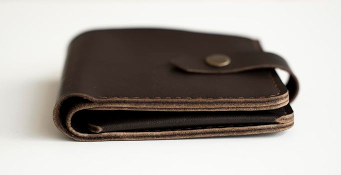 Side view of new dark brown genuine leather wallet with banknotes and credit card inside isolated on white background