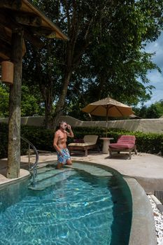 European man at infinity pool looking out over the ocean, luxury vacation private pool villa, luxury retreat