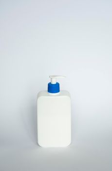 Large white cosmetic plastic bottle with pump dispenser pump and blue cap on white background. Liquid container for gel, lotion, cream, shampoo, bath foam