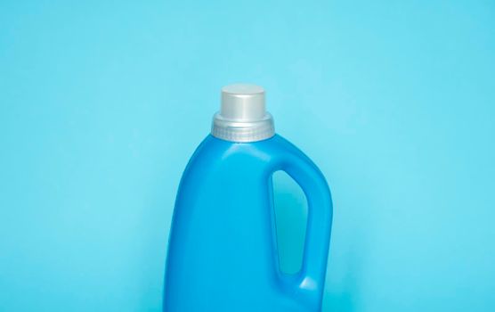 Blue plastic bottle stands on blue background. Conditioner or liquid powder for washing. Capacity with space for copying. Layout for logo application