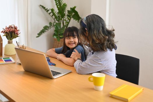 Adorable little asian girl using laptop with grandmother in living room. Multi generational, family and love concept.