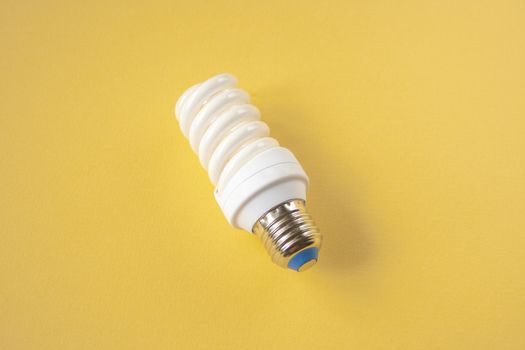 Energy saving light bulb on a yellow background. Economical consumption of electricity. The concept of nature conservation